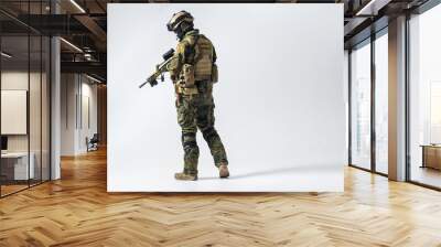 Full length side view serene defender in army clothes keeping assault rifle. Protection concept. Copy space Wall mural