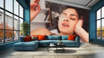 Girl laying at the bed and enjoying her day at home with cannabis Wall mural