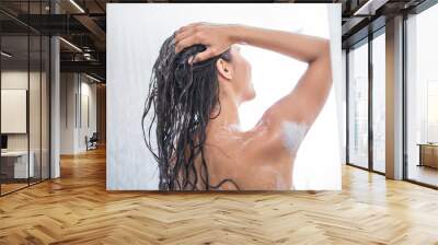 Girl using shampoo while taking shower in bright bathroom. She turning back to camera Wall mural