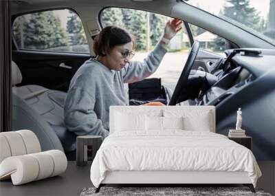 Girl with loss of leg function sitting in the car on parking space for disabled people Wall mural