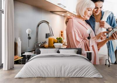 Grandmother and adult granddaughter using digital tablet in kitchen Wall mural