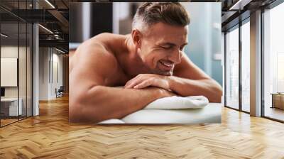 Handsome young man with closed eyes lying on massage table Wall mural