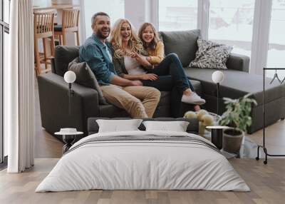 Happy family sitting on comfortable couch at home Wall mural