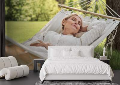 Happy mature female sleeping in hammock outdoors Wall mural