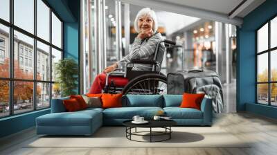 Happy mature lady on disabled carriage waiting for trip at hall Wall mural