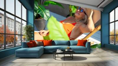 Happy mature woman lying on deckchair outdoors Wall mural