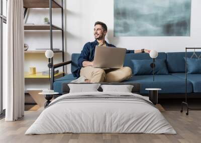 Happy youthful guy working at home via computer Wall mural