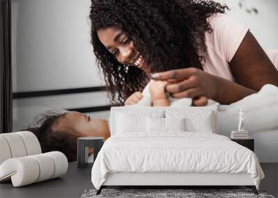 Joyful Afro American woman holding hand of baby girl Wall mural