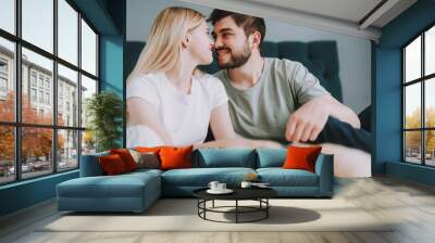 Joyful young loving couple sitting in the bedroom while expressing love Wall mural