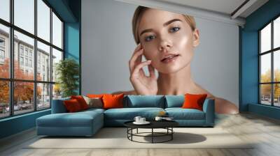 Laconic portrait of attractive relaxed young woman gently touching her chin while standing against the grey background Wall mural