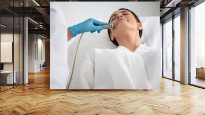 Lady on anti-age face roll massage procedure Wall mural