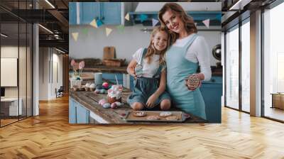 Little girl with mom showing egg shaped cookies Wall mural