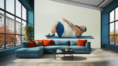 Man lying on a yoga mat doing sit ups Wall mural