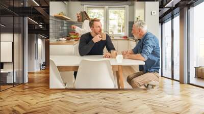 Mature father and young son drinking coffee and talking at the light kitchen Wall mural