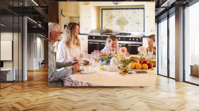 Mom, grandfather and two boys eating together on kitchen Wall mural