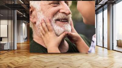 Old smiling man and his granddaughter looking each other Wall mural