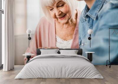 Old woman looking at thermometer readings and smiling Wall mural