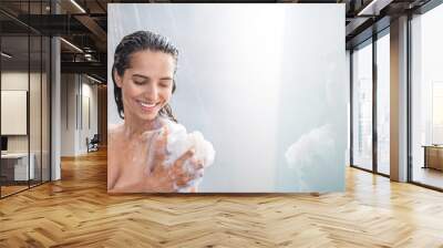 portrait of beaming woman rubbing body with foam while standing under steam of water. copy space Wall mural