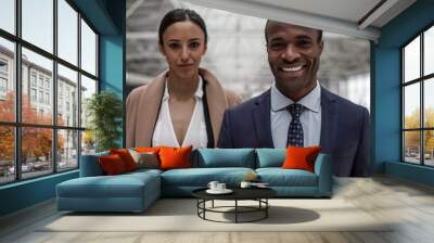 Portrait of cheerful cute young businessman and businesswoman in formal clothes are standing together and looking at camera with joy. Focus on african man Wall mural