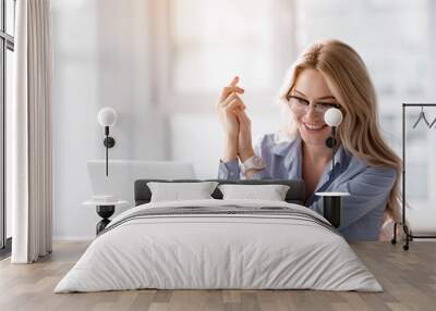 Portrait of excited businesswoman looking at laptop with satisfaction. She is having seat at her working desk and smiling Wall mural