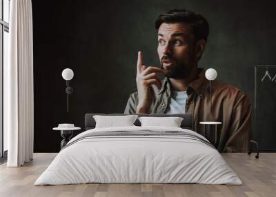 Portrait of thoughtful bearded man gesticulating hand while having interesting idea. He isolated on dark background Wall mural