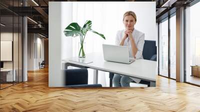 Portrait of young lady in white lab coat using computer at work. She is looking at camera with nice smile Wall mural