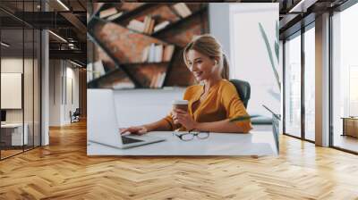 Positive businesswoman in her office working on the laptop Wall mural