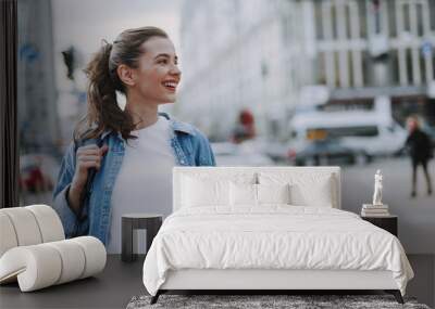 Pretty smiling young female walking around city Wall mural