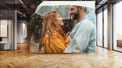 Profile of loving couple spending date outside. They are standing under umbrella and looking at each other with care and smile Wall mural