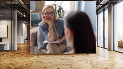 Psychologist with clipboard looking attentively at patient Wall mural