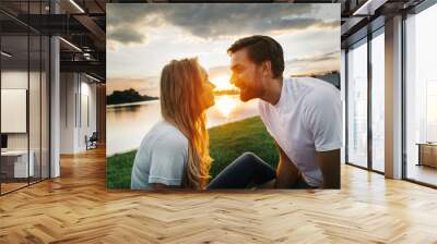 Side view beaming woman speaking with laughing bearded male during warm summer evening. They relaxing near river Wall mural