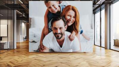 Smiling man and woman laying on bed with kids Wall mural