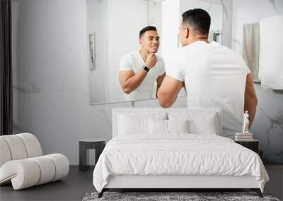 Smiling young man touching his chin before mirror Wall mural