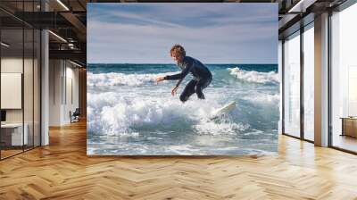 Surfing man enjoying waves at the cold ocean water while training during the summer Wall mural