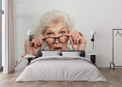 Surprised senior lady adjusting her glasses Wall mural