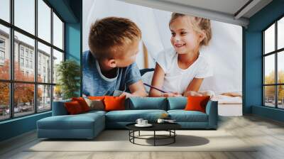 Two smiling children drawing together at home Wall mural