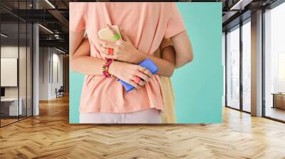 Unrecognizable girl embracing her bestie and holding two smartphones at the each hands Wall mural