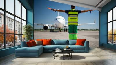 Welcome back. Back view of airport worker looking at passenger plane and signaling Wall mural