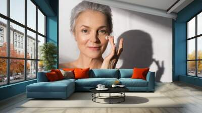 Woman applying cosmetic cream on clean hydrated skin portrait Wall mural