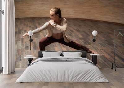 Young beautiful lady looking into the distance while practicing chi gong pose with her hand on the shoulder Wall mural