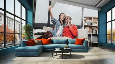 Young couple in love expressing enjoyment while resting inside and making selfie with tablet. Copy space in right side Wall mural