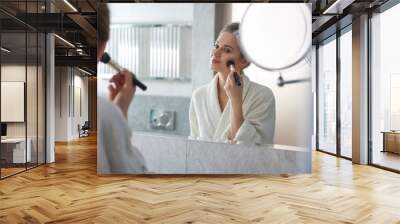 Young lady laying powder blusher on cheek Wall mural