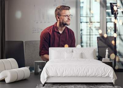 Young man is sitting with notebook at work Wall mural