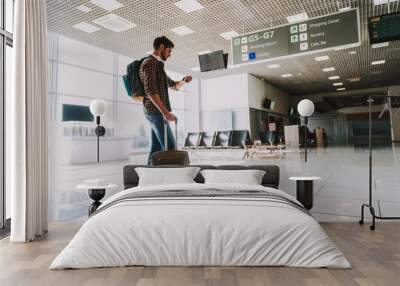 Young man is waiting for flight indoors Wall mural