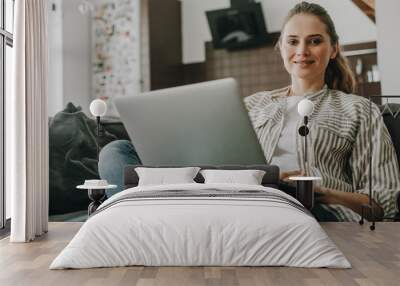 Young smiling female working on laptop at home Wall mural