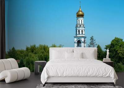 Landscape view of beautiful belfry on the riverside between lush greens Wall mural