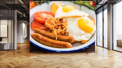 Typial breakfast with eggs, tomato, onion rings and sausage on plate Wall mural