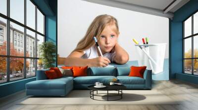 Beautiful blond girl of seven years draws Wall mural