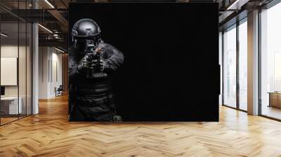 Airsoft player in an outfit with weapons on a black background Wall mural