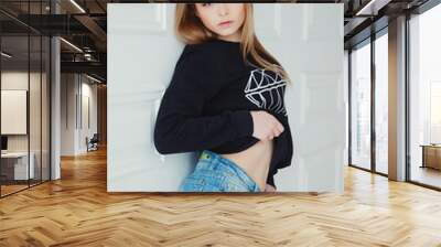 Studio photo of beautiful woman with sportive body in a black sweatshirt and jean shorts Wall mural